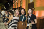 Three woman smiling for camera holding glasses of wine standing outside