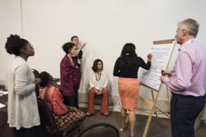 People standing around easel discussing things and writing list